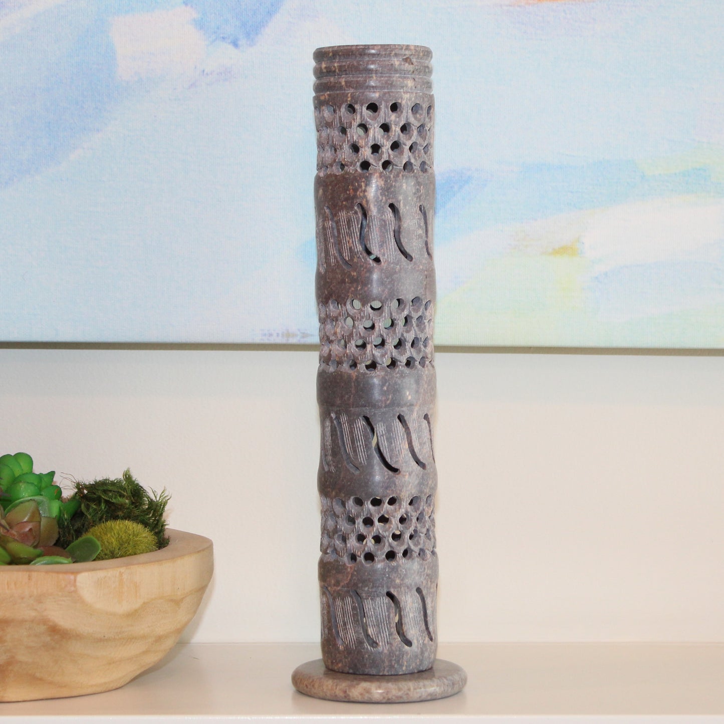 Decorative cylindrical object with patterns on a shelf with a blurred background