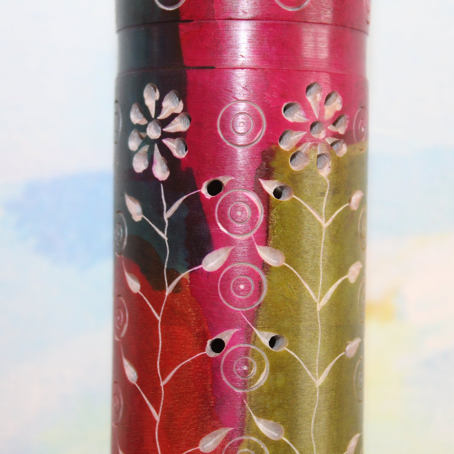 Decorative cylindrical container with floral patterns on a colorful background