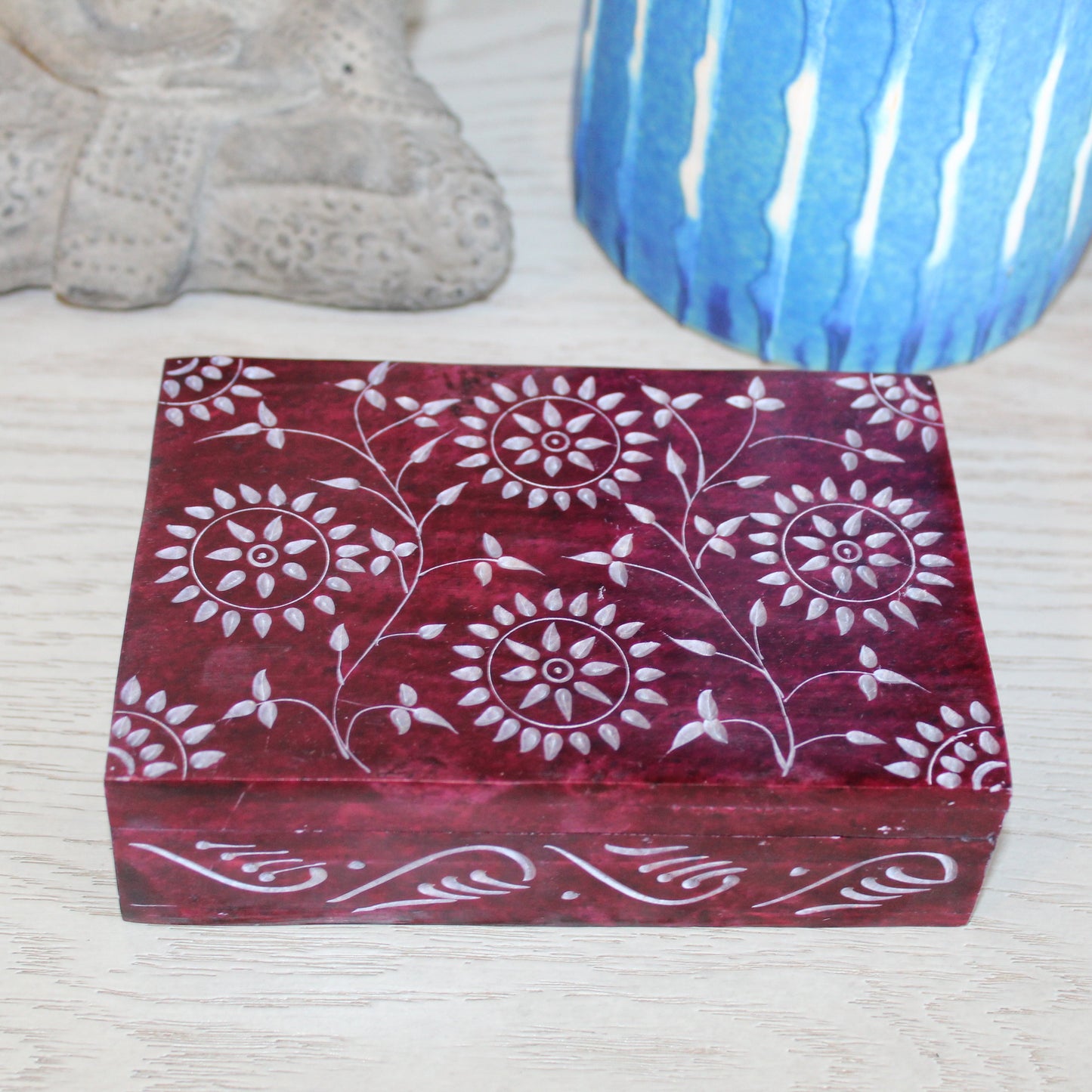 Decorative wooden box with floral patterns on a textured surface