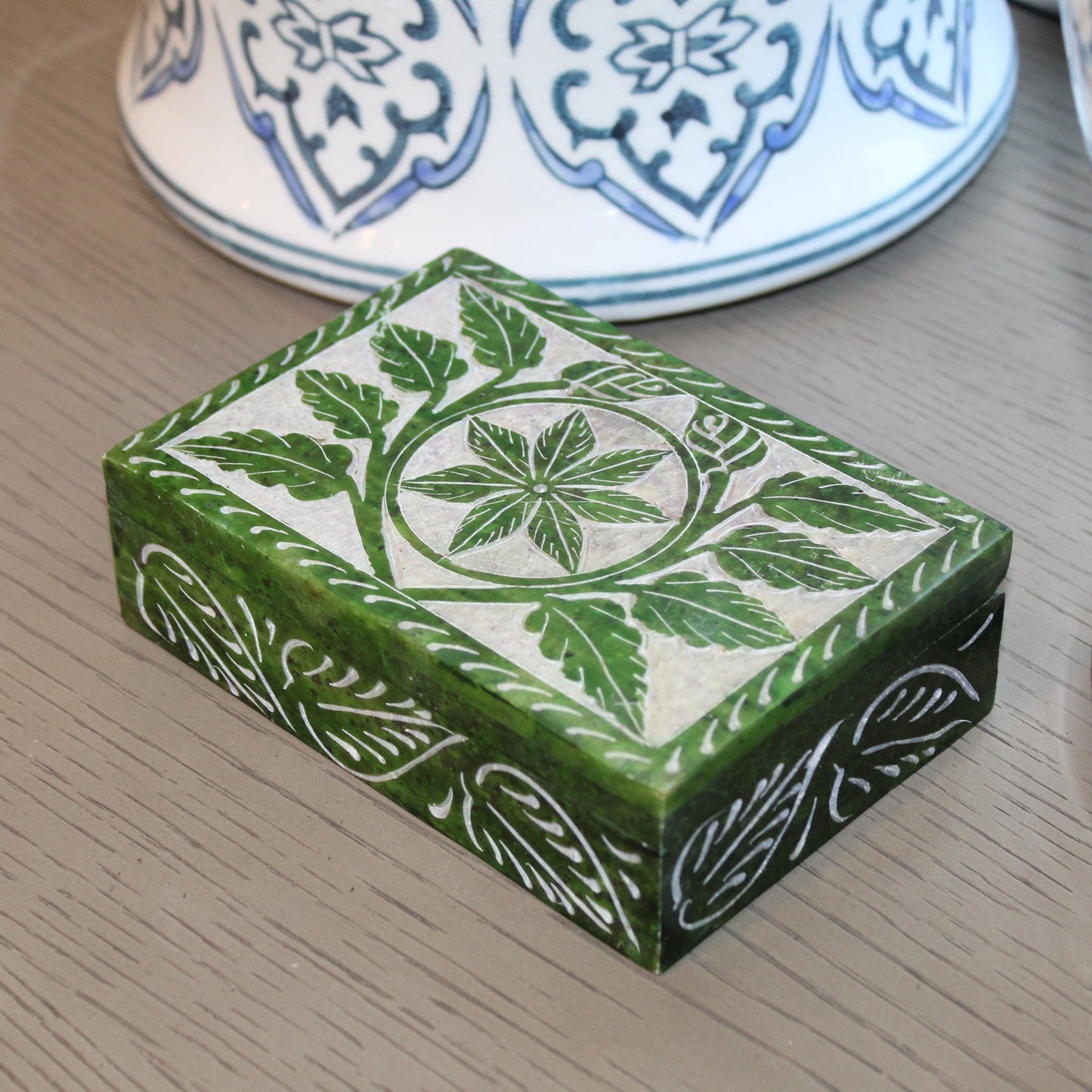 Green decorative box with floral patterns on a wooden surface