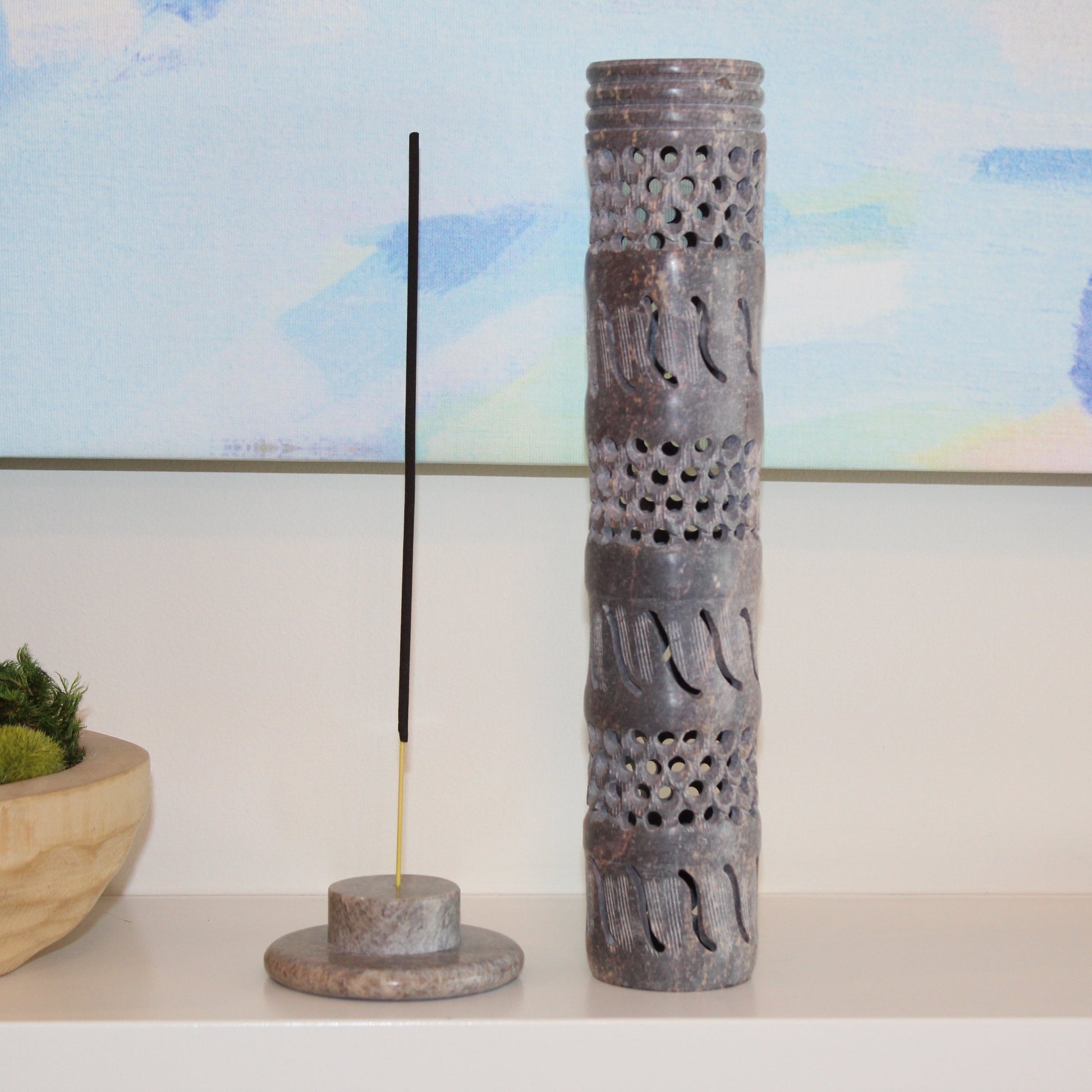 Decorative incense holder with a single incense stick on a shelf with a blurred background