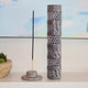 Decorative incense holder with a single incense stick on a shelf with a blurred background