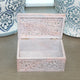 Wooden jewelry box with intricate carvings on a wooden surface with decorative vases in the background.