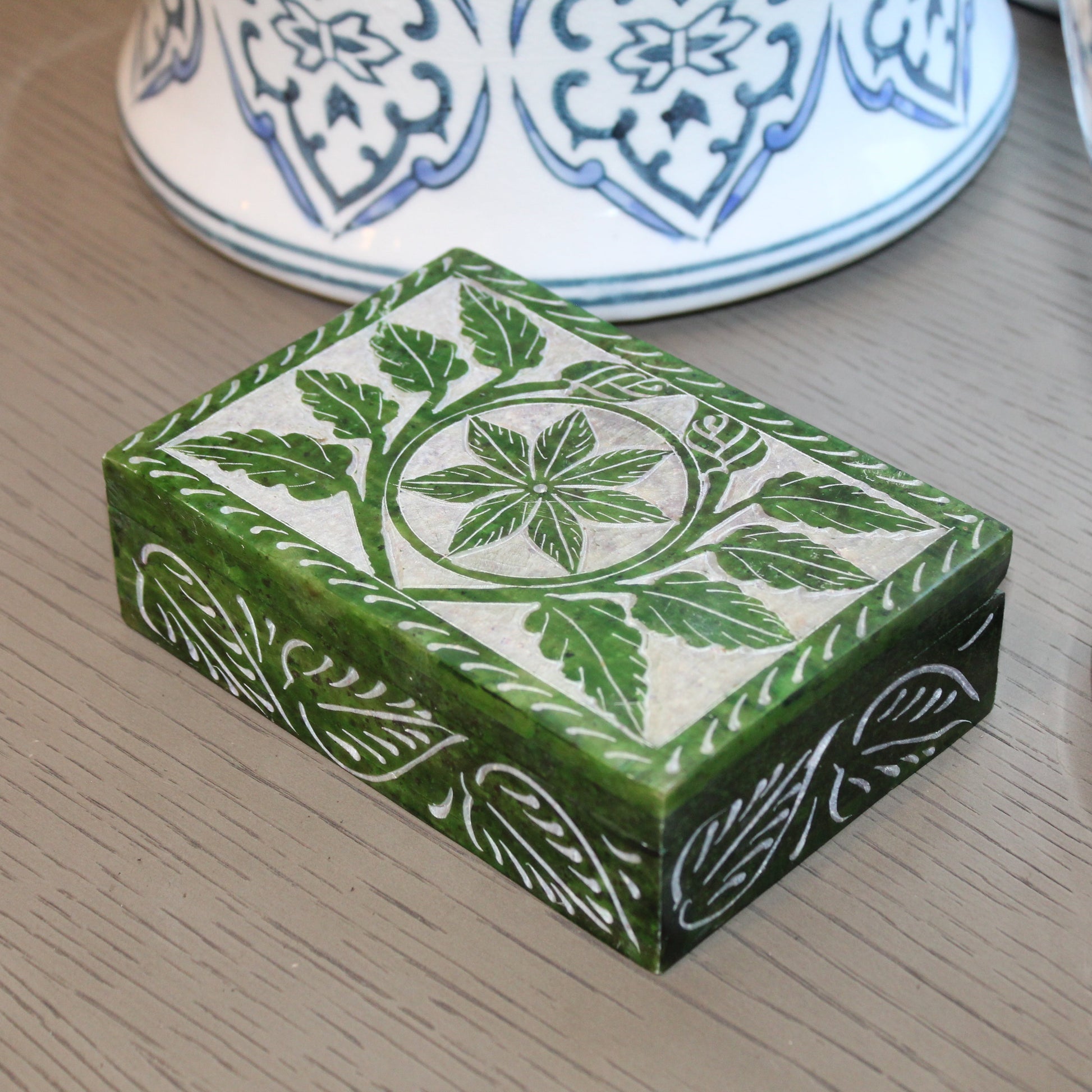 Green decorative box with floral patterns on a wooden surface