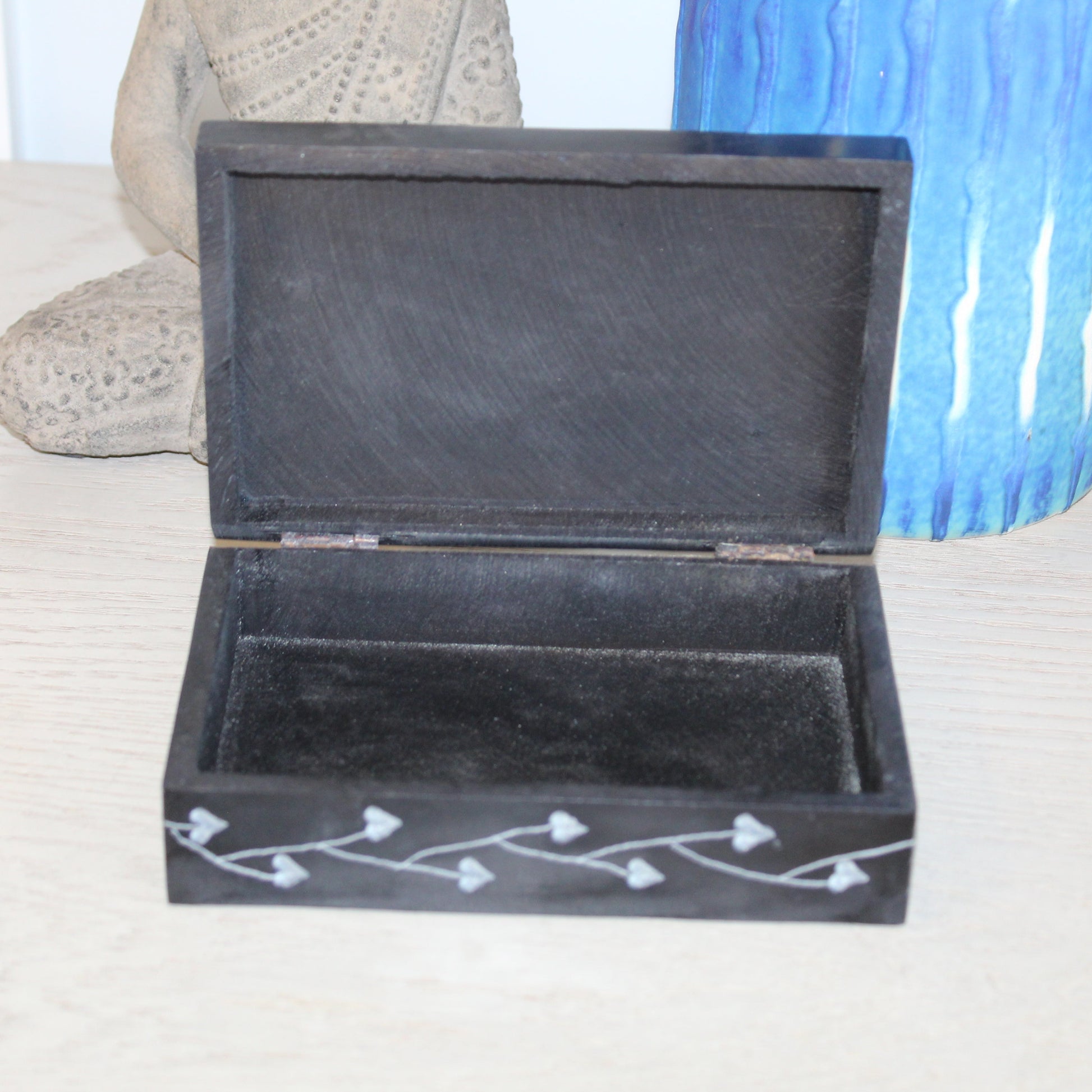 Black jewelry box with white designs on a light surface